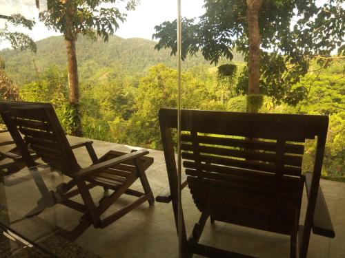 two chairs sitting on a porch looking out at the mountains at Evergreen Villa - Sinharaja in Deniyaya