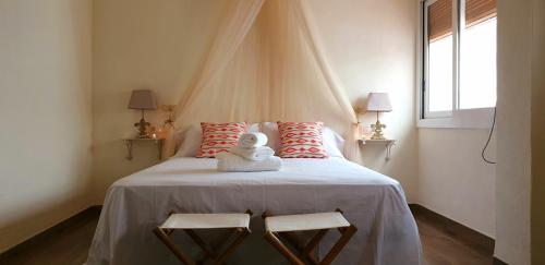 a bedroom with a large bed with two chairs at Les Llambrich - Apartamentos turísticos in L'Ampolla