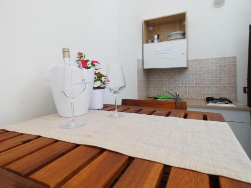 two wine glasses sitting on a wooden table in a kitchen at Camera Tonnarella in San Vito lo Capo