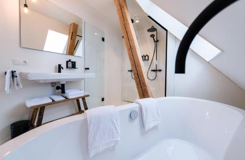 a bathroom with a white tub and a sink at Nobel Houses & Lofts in Ballum