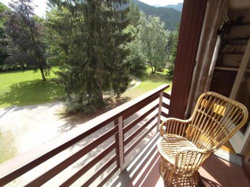 a wicker chair sitting on a porch looking out at a yard at MEADOWS Apartment in Ponte di Legno