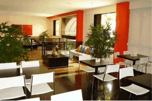 uma sala com mesas e cadeiras brancas e plantas em Entremares Hotel no Rio de Janeiro