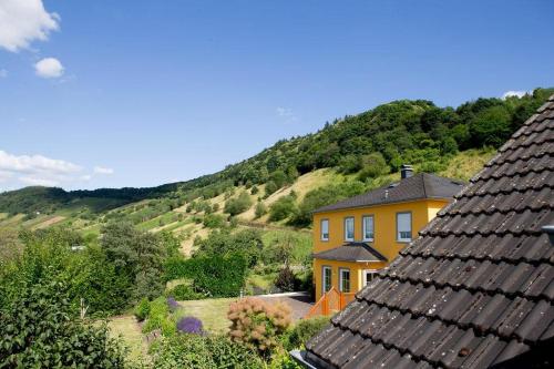 ein gelbes Haus mit einem Berg im Hintergrund in der Unterkunft Moseltraum-Villa Kenn bei Trier in Kenn