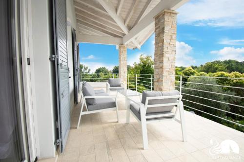a porch with white chairs and a view of trees at Villa Bocciolo del Garda in Manerba del Garda