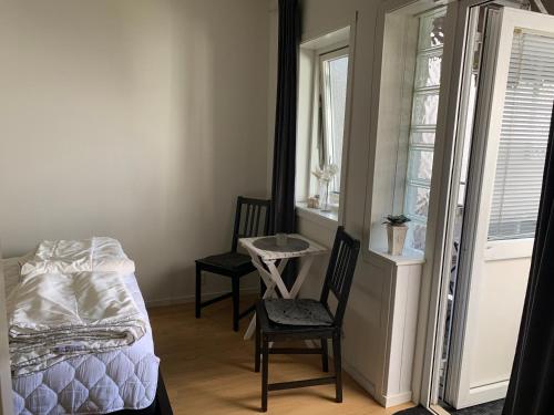a bedroom with a bed and two chairs and a window at Villa Tullgatan Borgholm in Borgholm