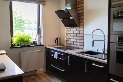 a kitchen with black cabinets and a sink and a window at Apartament nad jeziorem Drwęckim Oaza in Ostróda