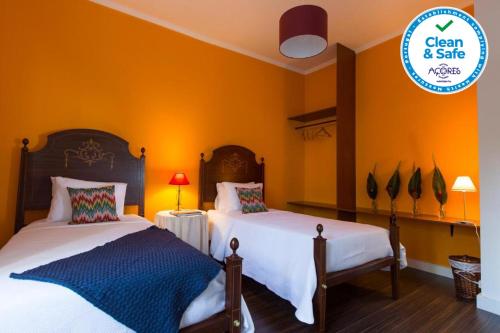 2 camas en una habitación con paredes de color naranja en Casa Villa Cottage, en Ponta Delgada