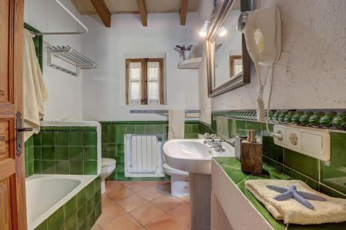 a green and white bathroom with a sink and a tub at Mena in Pollença