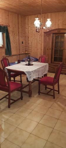 einen Esstisch mit roten Stühlen, einem weißen Tisch und einem Chairsktop in der Unterkunft Ela`s Ferienoase Haus Ketsching in Görcsönydoboka