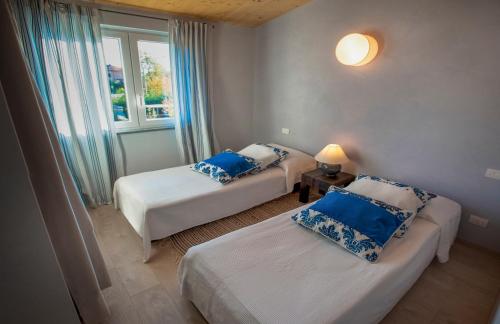 a room with two beds with blue pillows and a window at La Rosa Gialla Bio Apartments & rooms in Barolo