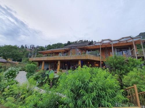 a large wooden building in the middle of a garden at Sapa Clay House - Mountain Retreat in Sa Pa