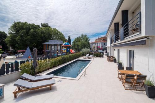patio z basenem, stołami i krzesłami w obiekcie CURICTA Design Apartments w Krku