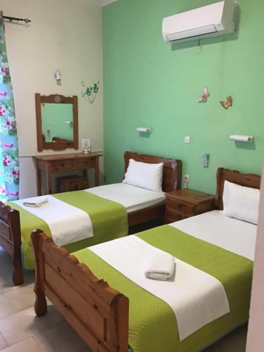 two beds in a room with green walls at Corfu Sunflower Apartments in Benitses