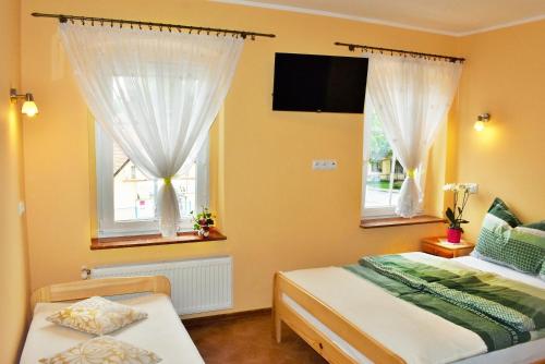 a bedroom with two beds and two windows at Pokoje nad rzeką in Kudowa-Zdrój