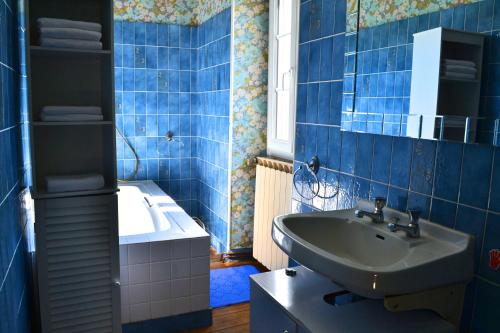 uma casa de banho em azulejos azuis com um lavatório e uma banheira em Gite Le Masgiral em Saint-Christophe