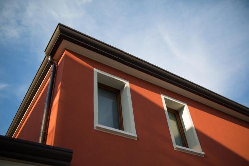 a red building with three windows on it at Guest House Bella Onda in Tessera