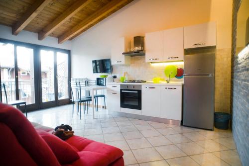 a kitchen with white cabinets and a red couch at Carmel Self-Apartment in Castelnuovo del Garda