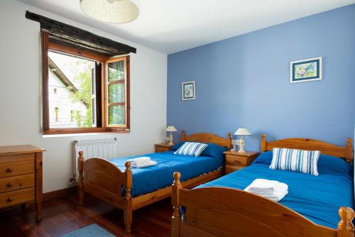 2 camas en un dormitorio con paredes azules en Casa Rural Areano, en Escoriaza