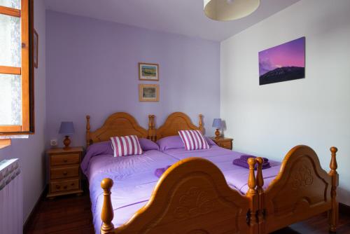 a bedroom with a wooden bed with purple sheets at Casa Rural Areano in Escoriaza