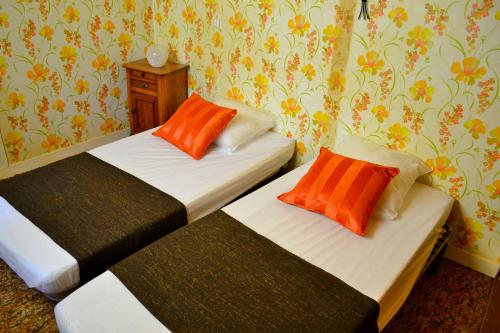 two beds in a room with orange pillows on them at Gite Le Masgiral in Saint-Christophe
