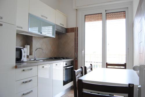 a kitchen with white cabinets and a table with chairs at Gaiavacanze Beach Apartment in Bordighera
