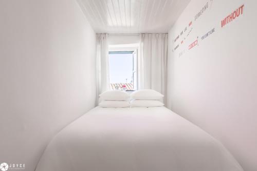 - un lit blanc avec deux oreillers dans une chambre dotée d'une fenêtre dans l'établissement InLoveApartments - Typical Portuguese Tiles, à Lisbonne