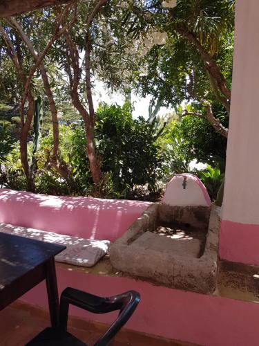 a pink couch and a table and a chair at dammuso rosa in Pantelleria