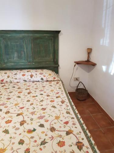 a bed with a green head board in a bedroom at dammuso rosa in Pantelleria
