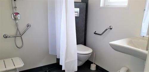La salle de bains blanche est pourvue de toilettes et d'un lavabo. dans l'établissement Camping le Frêche à l'Âne, à Pléboulle