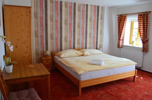 a bedroom with a bed and a wooden table at Pension U Kostela in Frymburk