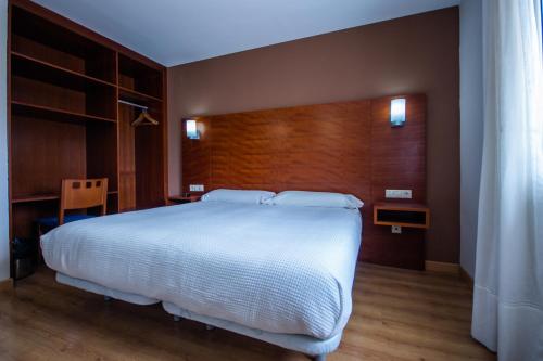 a bedroom with a large white bed and a desk at Pension Viella Asturias in Viella