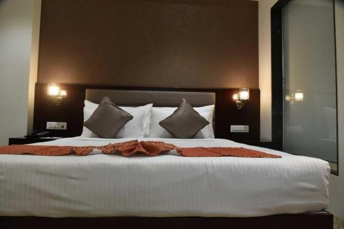 a bedroom with a large bed with white sheets and pillows at Pride Hotel & Convention Centre Indore in Indore
