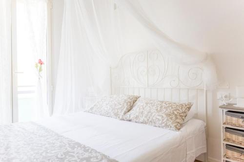 un letto bianco con testiera bianca e finestra di Sirena Apartment a Riccione