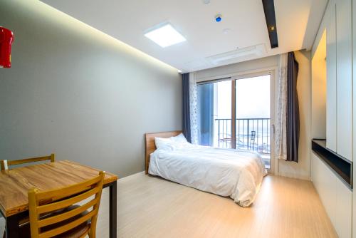 Sokcho Daemyung Pension Samsung Home prestige في سوكشو: غرفة نوم بسرير وطاولة ونافذة