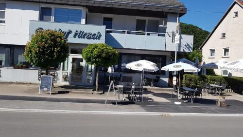 um restaurante com mesas e guarda-sóis em frente a um edifício em Hotel Restaurant Hirsch em Schmiechen