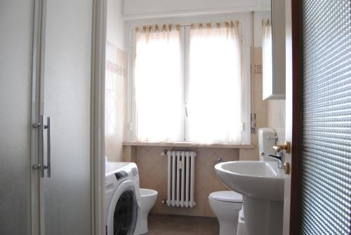 a bathroom with a sink and a toilet and a window at Gaiavacanze Beach Apartment in Bordighera
