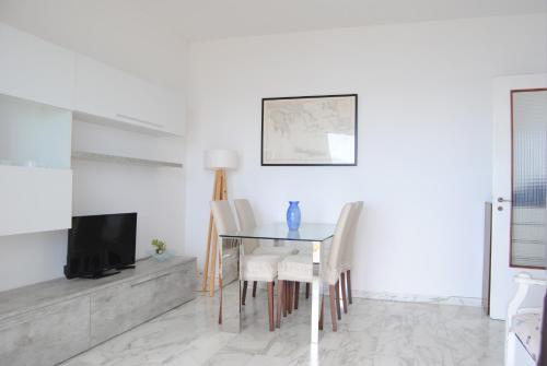 a dining room with a table and chairs and a tv at Gaiavacanze Beach Apartment in Bordighera