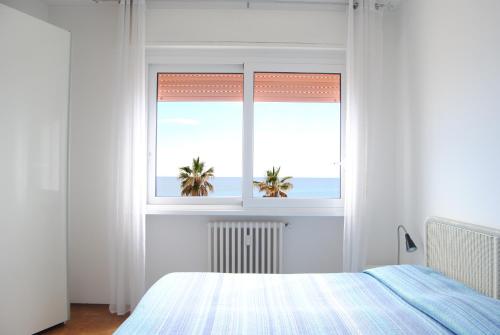 a bedroom with a window with a view of the ocean at Gaiavacanze Beach Apartment in Bordighera