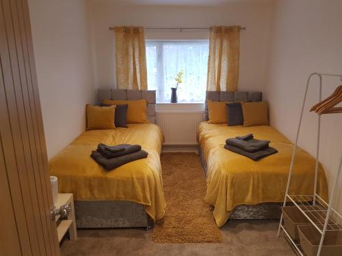 two beds in a room with yellow sheets and a window at Rosie flanagan's in Skegness