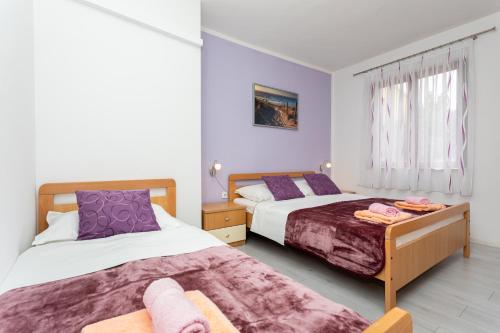 two beds in a bedroom with purple and white at Santima Apartments in Baška
