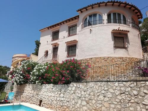 um edifício no topo de uma parede de pedra com flores em Apartamento Maya, private Pool em Benissa