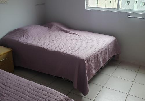 a bedroom with a purple bed and a window at Apartamento confortável em Meia Praia - 200 metros da praia in Itapema