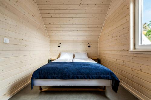 ein Schlafzimmer mit einem Bett in einer Holzwand in der Unterkunft Na Klifie Wypoczynek&Spa in Rewal