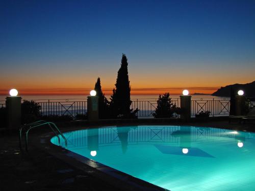 a swimming pool with a sunset in the background at Dina's Paradise in Agios Gordios