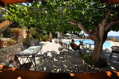 a woman sitting at a table next to a pool at Dina's Paradise in Agios Gordios