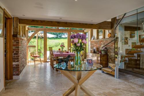 un comedor con una mesa de cristal con flores. en South Park Farm Barn en Andover