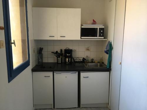 a kitchen with white cabinets and a sink and a microwave at Vieux-boucau entre lac et océan in Vieux-Boucau-les-Bains