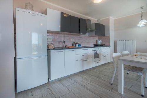 a kitchen with white cabinets and a table and a refrigerator at Apartments Apartim Piran in Piran