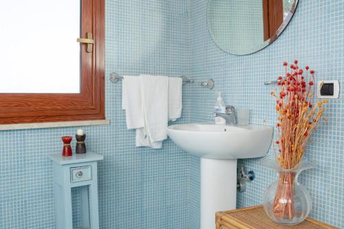 Baño de azulejos azules con lavabo y espejo en Terrazza sul Plemmirio, en Siracusa