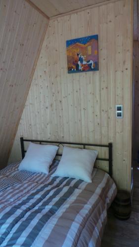 Cama en habitación con pared de madera en SARL A Faire à Cheval, en Parzac